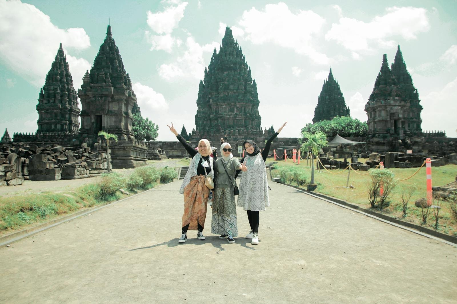 Three women pose happily at the historic Prambanan Temple, a cultural landmark in Jogja, Indonesia.