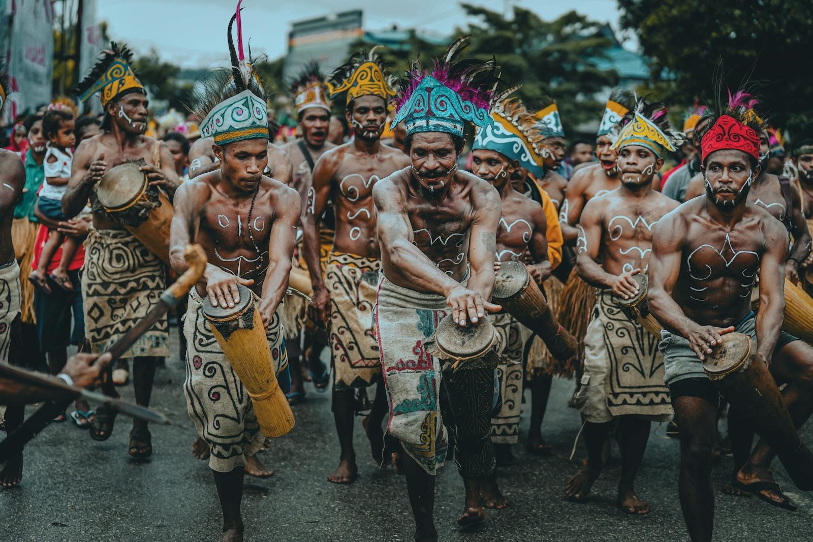 Colorful traditional parade in Papua showcasing dancers in tribal costumes playing drums.